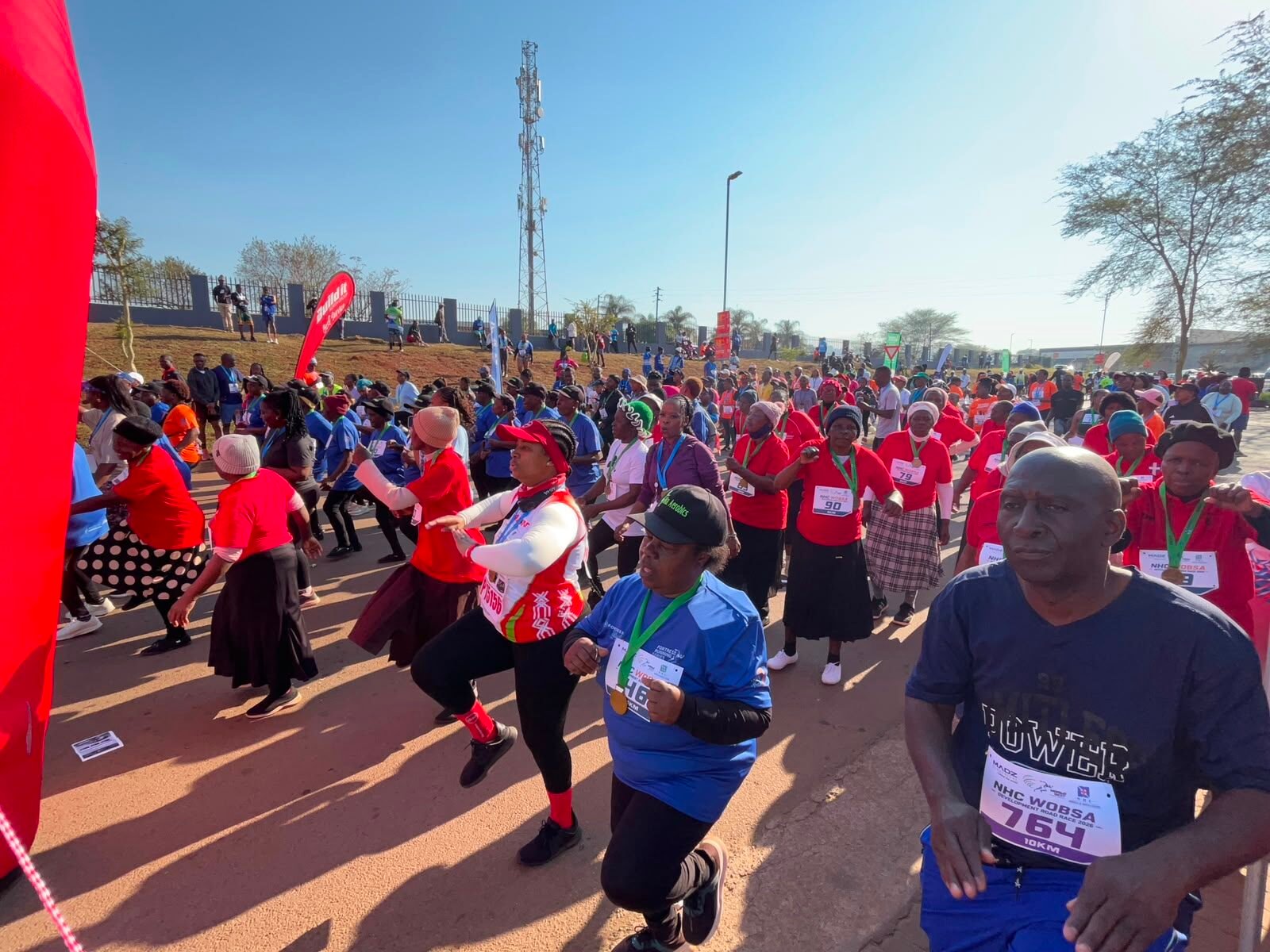 A large group of participants jogging and dancing together at the race warm-up