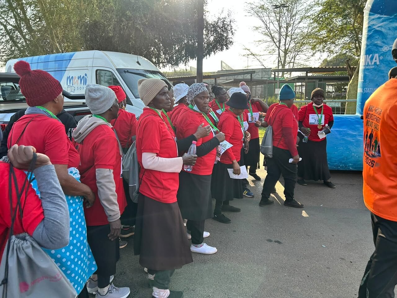 A group of elderly women in matching red shirts gathered at the road race