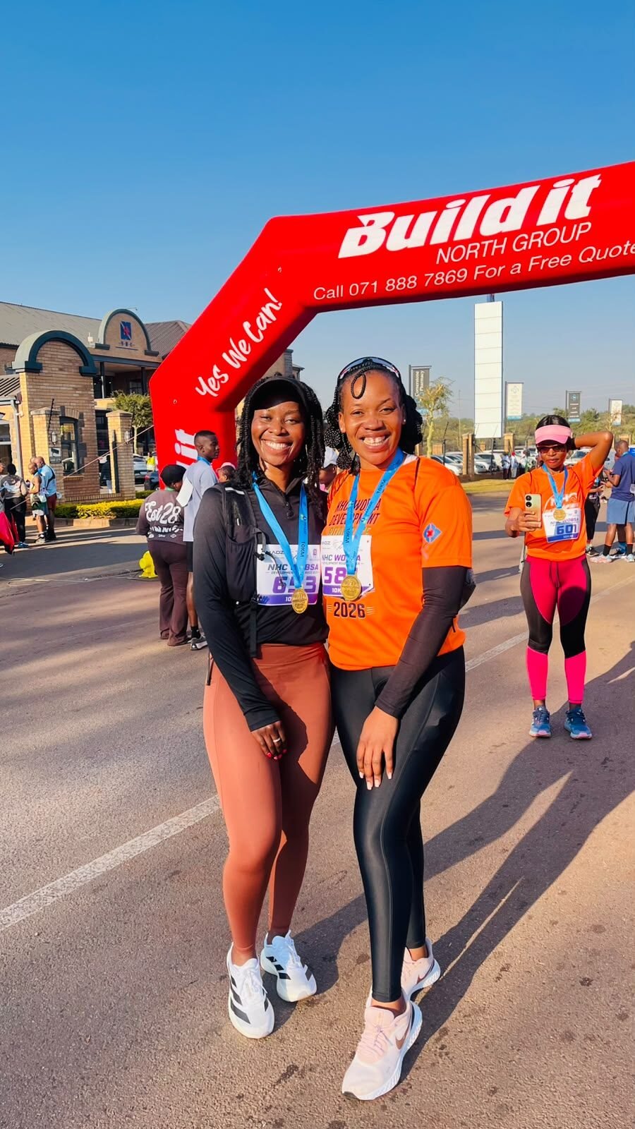 Two finishers celebrating with their medals under the finish arch